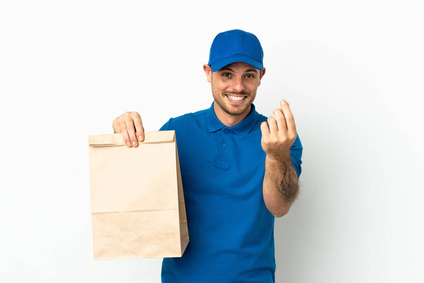 Бразилець бере сумку з харчами, відокремленими на білому фоні, і робить грошовий жест. - Фото, зображення