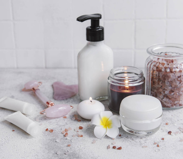 Спа набор, эфирное масло, соль для массажа, свечи и цветы франджипани на сером бетонном фоне - Фото, изображение