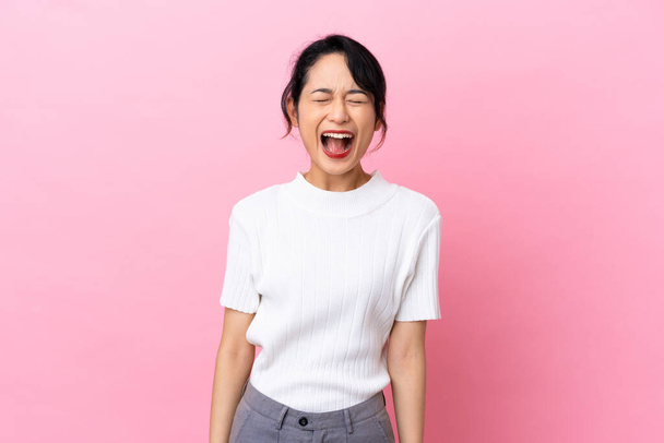 Young Vietnamese woman isolated on pink background shouting to the front with mouth wide open - 写真・画像
