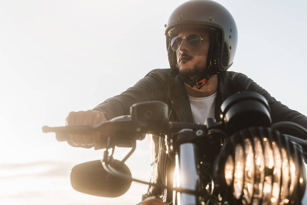 Portrait of biker looking away, sitting on his vintage motorcycle - Φωτογραφία, εικόνα