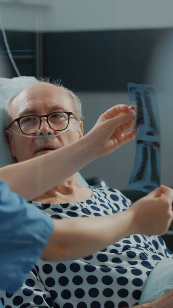 Sairaanhoitaja selittää röntgentulokset sairaalle potilaalle - Valokuva, kuva