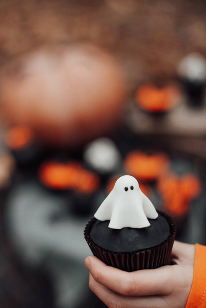 Mann hält Cupcake in der Hand, Konzept für das traditionelle Herbstfest Halloween - Foto, Bild