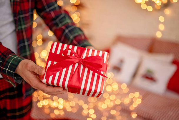 Adult man holds in his hand a box with a gift for Advent holiday. Happy New Year and Merry Christmas - Photo, Image