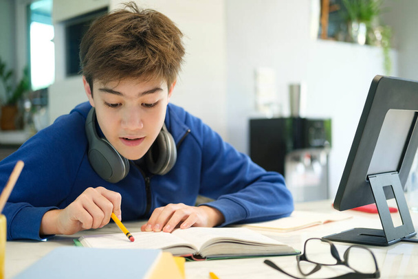 Online-Fernunterricht. Ein Schuljunge lernt zu Hause und macht Hausaufgaben. Ein Fernstudium zu Hause. - Foto, Bild