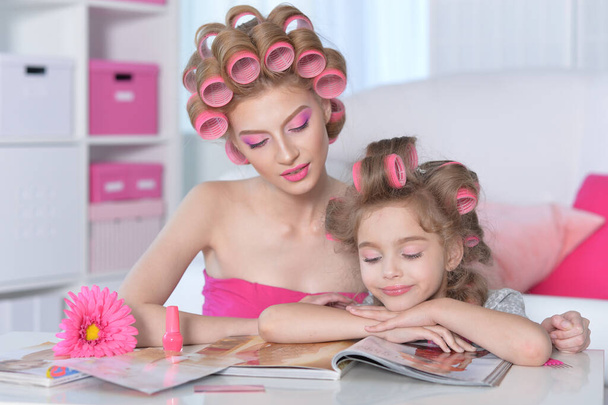 portrait of happy  mother and little daughter with hair curlers at home - Valokuva, kuva