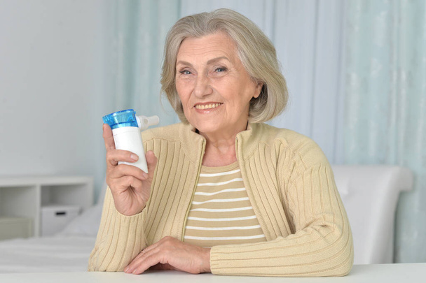 Portrait of sick senior woman sitting  with inhaler  - Fotografie, Obrázek