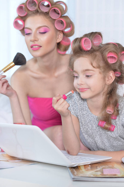  mother and little daughter with hair curlers applying  make up  - Foto, afbeelding