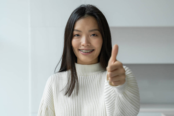Asian woman smiles and gives a thumbs up to the camera - Foto, afbeelding