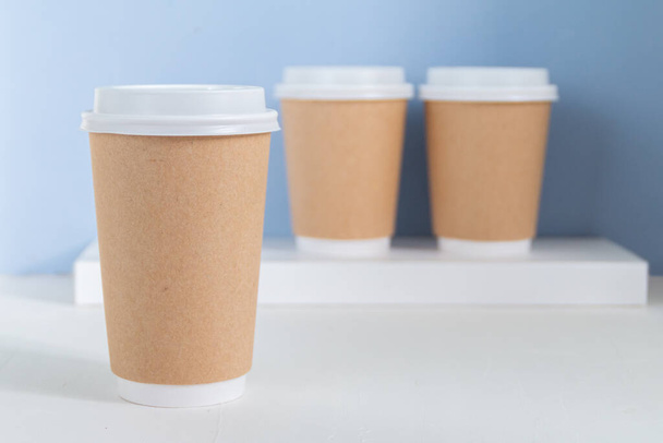 empty paper cup to go against light blue background - 写真・画像