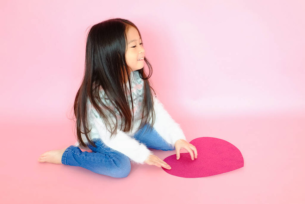 Portrait beautiful cute asian child girl on pink background with red heart sign, valentine day in love concept - Photo, Image