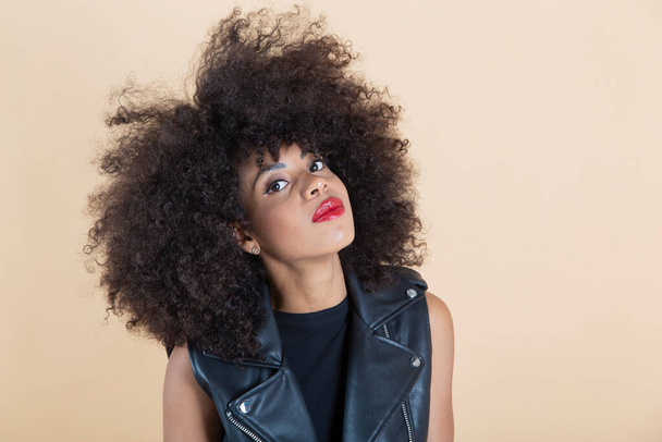 pretty afro american woman in a leather vest beige background - Photo, Image