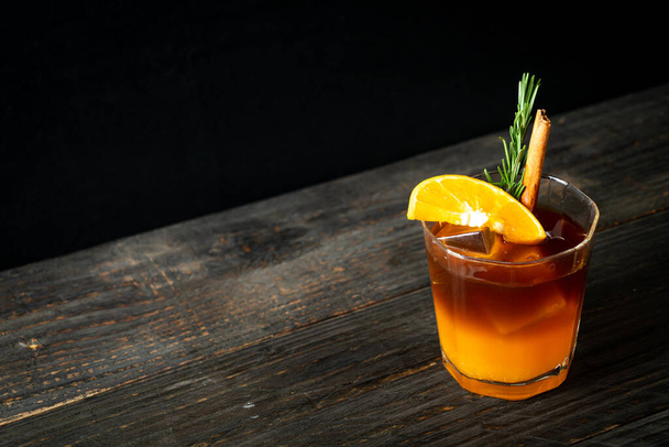 A glass of iced americano black coffee and layer of orange and lemon juice decorated with rosemary and cinnamon - 写真・画像