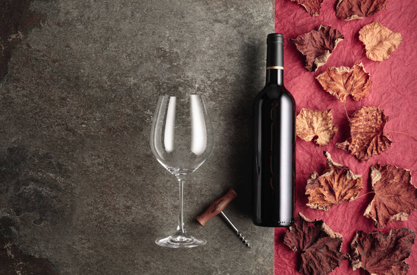 Bottle of red wine with corkscrew and dried vine leaves on an vintage background. Top view with copy space. - Фото, изображение