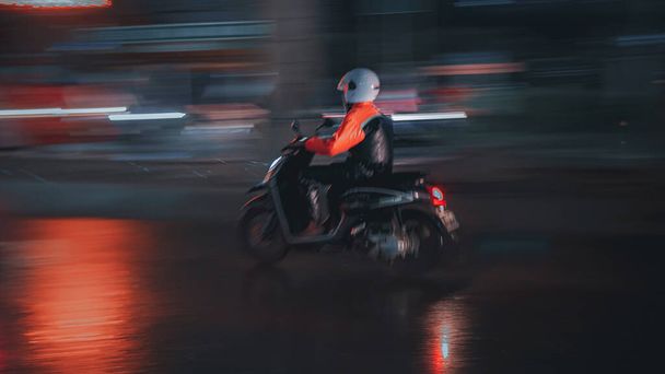 A side view of a motorcyclist on the road at night, light trails in the background - Valokuva, kuva