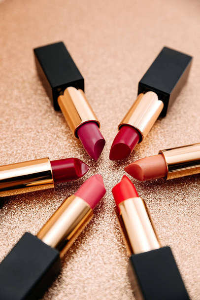 A closeup shot of red-toned lipsticks on a rough surface - Foto, afbeelding