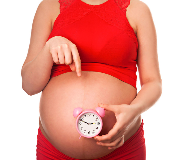 Pregnant woman holding alarm clock expecting to deliver soon - Fotó, kép