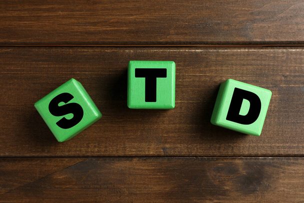 Abbreviation STD made with cubes on wooden table, flat lay - Foto, immagini