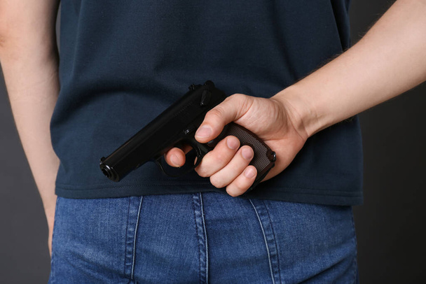 Man hiding gun behind his back, closeup view - Foto, Imagem