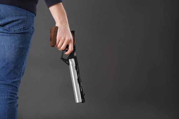 Gun shooting sport. Man holding standard pistol on dark background, closeup. space for text - Fotoğraf, Görsel