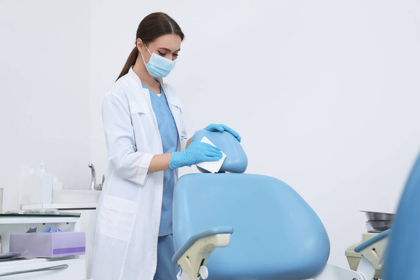Professional dentist in white coat and medical mask cleaning workplace indoors - Foto, imagen