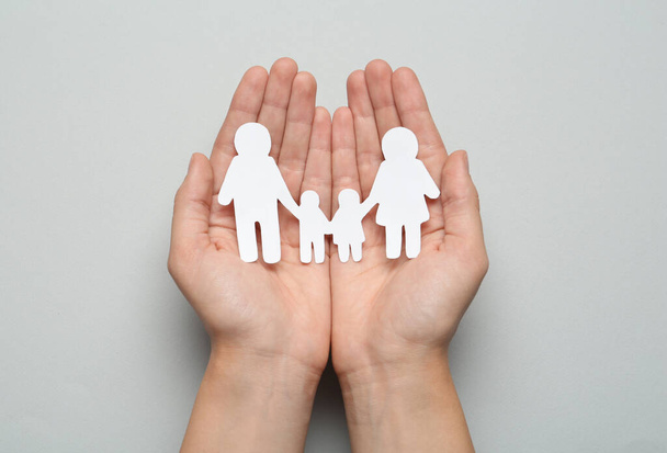 Woman holding paper family cutout on light grey background, top view - Foto, imagen