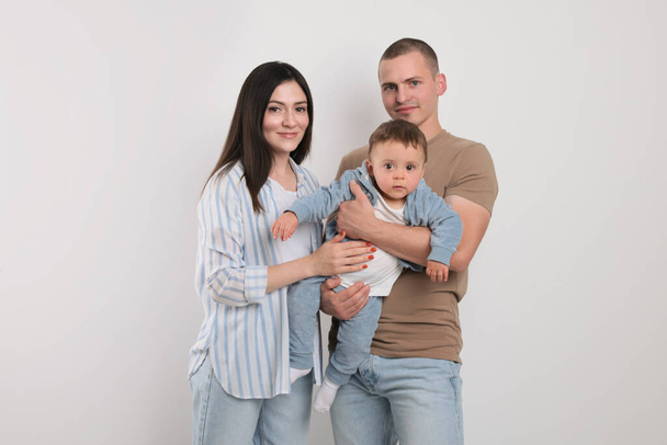 Portrait of happy family with little child on light background - Photo, Image