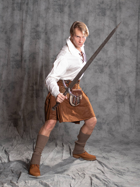 A young man in a leather kilt and a white lace-up blouse. A Scottish knight - Valokuva, kuva