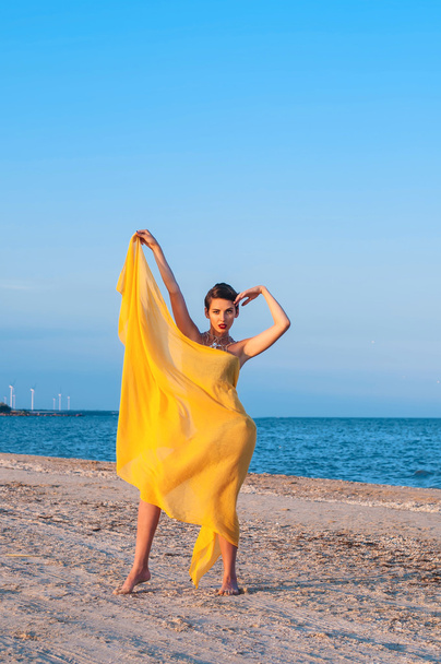 Young girl on the beach  yellow pareo - Fotoğraf, Görsel