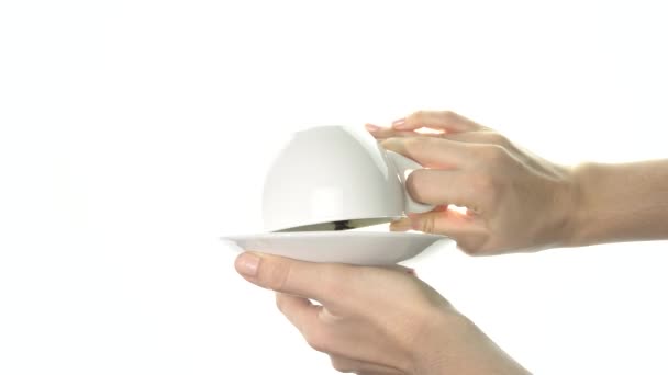 A női kezek megfordítanak egy fehér poharat, amiben a kávéültetvények szív alakúak. Közelkép - Felvétel, videó