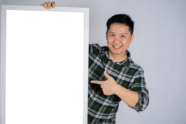 A 40-year-old man smiles, his hand pointing at an empty picture frame. Can put advertising media, text, images. - Foto, Bild