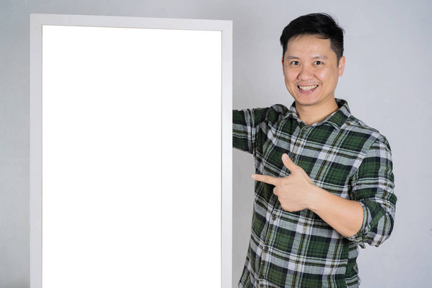 A 40-year-old man smiles, his hand pointing at an empty picture frame. Can put advertising media, text, images. - Foto, Imagem