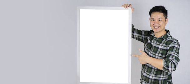 A 40-year-old man smiles, his hand pointing at an empty picture frame. Can put advertising media, text, images. - Photo, image