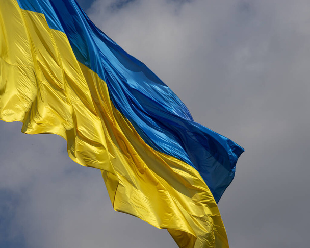 Україна прапор махав на вітер проти синього неба. - Фото, зображення