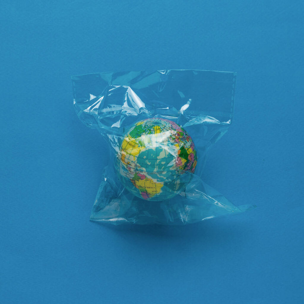 The globe is packed in a cellophane bag on a blue background. Flat lay. - Foto, afbeelding