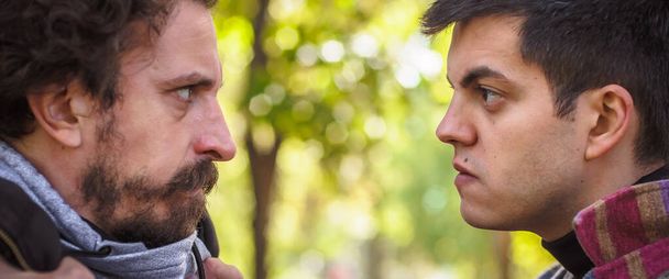Head to head conflict close-up. Two very angry, nervous and upset men in an aggressive and fierce quarrel on the verge of a physical confrontation and a fight - 写真・画像