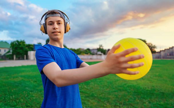 teen boy in posa con la palla in uno stadio, tiene la palla in mano, un campo da calcio con erba verde - sport e concetto di salute - Foto, immagini