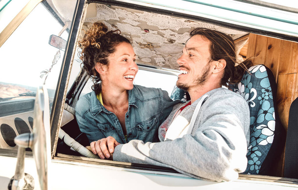 Hipster couple driving at roadtrip on oldtimer mini van transport - Travel lifestyle concept with indie people having fun in relax moment on minivan adventure trip - Warm bright filter - Photo, Image