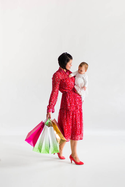  Frau hält Pakete. Mutter und kleines Kind kaufen ein. Weißer Hintergrund. Schwarzer Freitag. - Foto, Bild