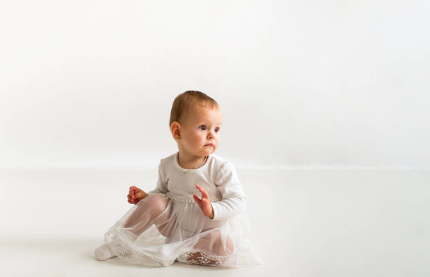 Cute baby on a white background in a white bodysuit. - Photo, Image