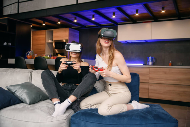 Girlfriends playing with excitement video games at home using vr glasses. Enjoying vacation time to spend leisure with friends. - Zdjęcie, obraz