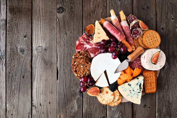 Charcuterie board de uma seleção de carnes, queijos e aperitivos. Visão aérea sobre um fundo de madeira escura. - Foto, Imagem