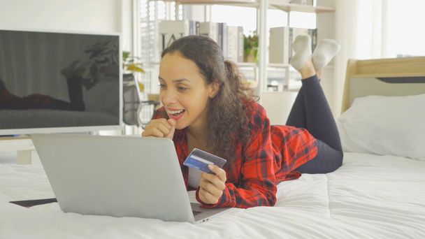Boldog latin üzletasszony, az emberek online vásárlás az interneten, a hitelkártya segítségével fizetni pénzt egy számítógép notebook laptop technológia eszköz, ágyon a hálószobában otthon. Életstílus. Alszik.. - Fotó, kép