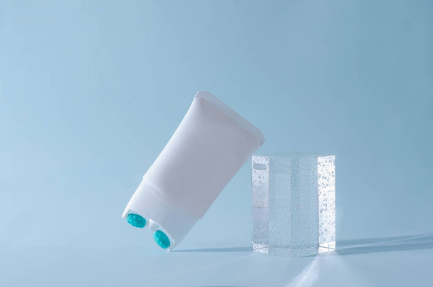 Ανόρθωση κρέμας με ακροφύσιο μασάζ σε λευκό σωλήνα σε μπλε φόντο με βάθρο από πλεξιγκλάς - Φωτογραφία, εικόνα