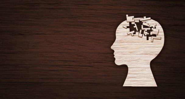 Symbol duševního zdraví. Lidská hlava silueta s puzzle vystřižené z dřevěného pozadí. - Fotografie, Obrázek