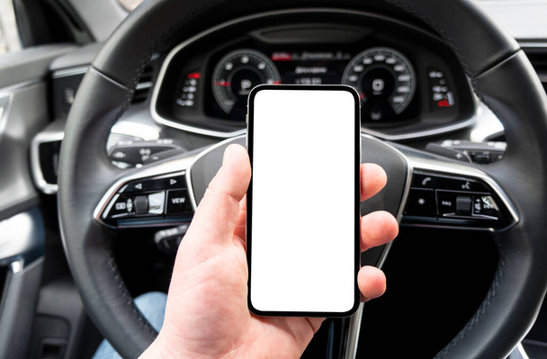Driver hand using smartphone in car. Smartphone in a car use for Navigate or GPS. Mobile phone with isolated white screen. Blank empty screen. copy space. Empty space for text. - Photo, Image