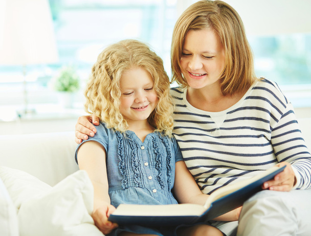 Girl and her mother reading a book - Foto, Imagen