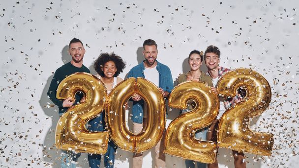 Group of young beautiful people in casual clothing carrying gold colored numbers and smiling - Foto, afbeelding