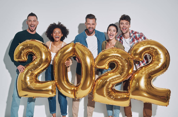Group of young beautiful people in casual clothing carrying gold colored numbers and smiling - Foto, Imagem
