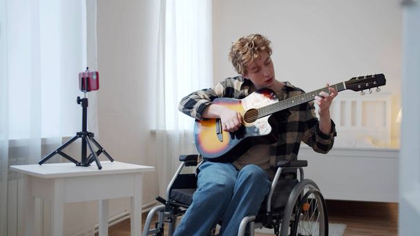 Un disabile sta girando un video su un telefono e suona la chitarra - Foto, immagini