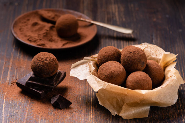 Lekkere pure chocolade truffels met cacao stof op een bruine achtergrond - Foto, afbeelding